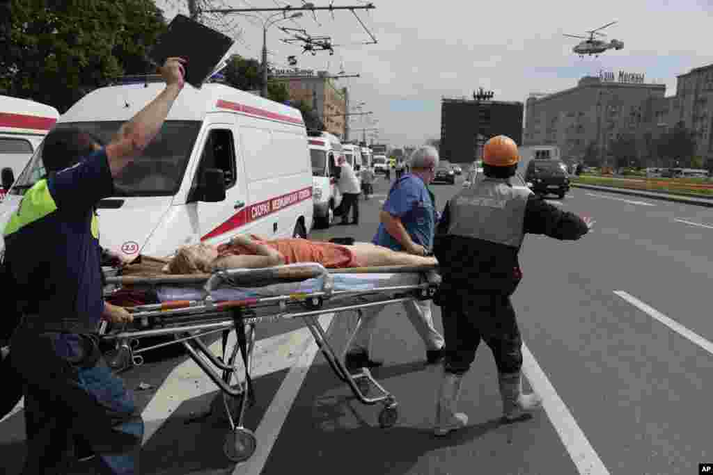 Petugas paramedik membawa seorang perempuan yang terluka ke sebuah helikopter medis di Moskow (15/7). (AP/Ivan Sekretarev)