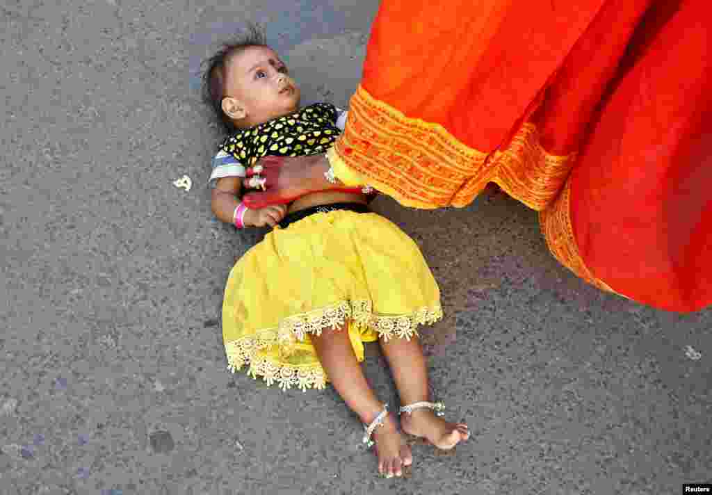 Seorang perempuan Hindu melangkahi anak perempuannya untuk meminta berkah dari Dewa Matahari pada festival keagamaan Chhat Puja di Kolkata, India.