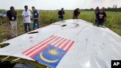 調查人員在烏克蘭東部查看MH17航班的一塊殘骸(2014年資料照)