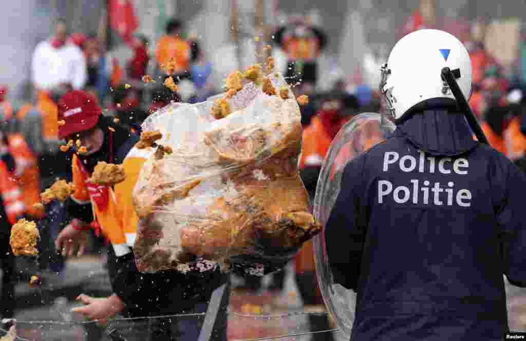 Seorang demonstran melempar sampah kepada polisi anti huru-hara dalam protes Serikat Buruh Eropa terhadap langkah-langkah penghematan, di pusat kota Brussels, Belgia. 