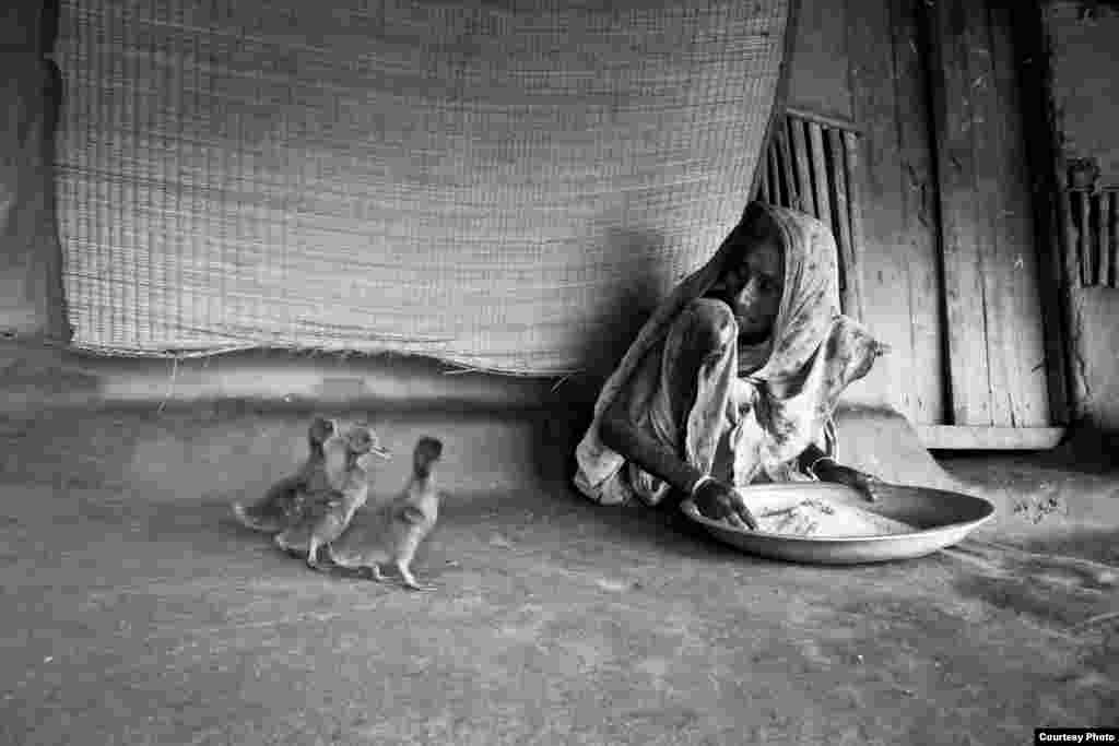 Juara pertama diraih Raihan Parvez dari Bangladesh dengan foto berjudul "Existence". Berlokasi di Gabura, Bangladesh, foto ini menggambarkan seorang perempuan, barangkali berusia sekitar 90 tahun, sedang membersihkan beras, sementara tiga ekor itik di dekatnya menunggu si nenek berpaling agar bisa mengambil beras.