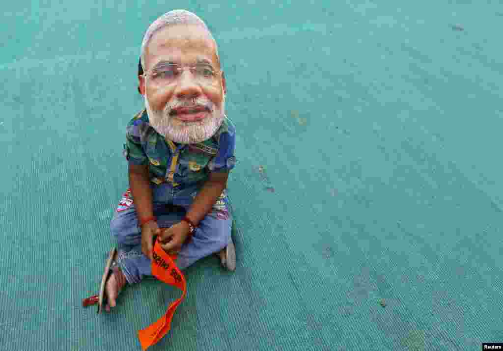 A boy wearing a mask of Hindu nationalist Narendra Modi, prime ministerial candidate for India's main opposition Bharatiya Janata Party (BJP), waits for the start of an election campaign rally being addressed by Modi in Kheralu town in the western Indian state of Gujarat.