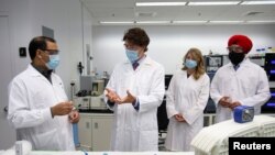 Perdana Menteri Kanada Justin Trudeau didampingi Menteri Inovasi, Sains, dan Industri Navdeep Bains (kanan) meninjau pembuatan vaksin di Dewan Riset Nasional, di Montreal, Quebec, Kanada, pada 31 Agustus 2020. (Foto: Reuters/Christinne Muschi)