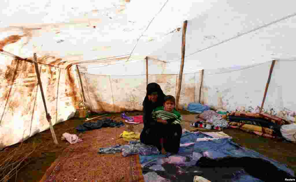 A Syrian refugee woman and her child sit in her makeshift tent in the town of Viransehir, southeast Turkey, February 10, 2013.