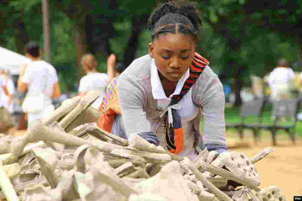 Seorang remaja putri memilih tulang-tulang simbolis untuk ditampilkan dalam instalasi "Sejuta Tulang" di taman National Mall, Washington DC (8/6). (VOA/Jill Craig)