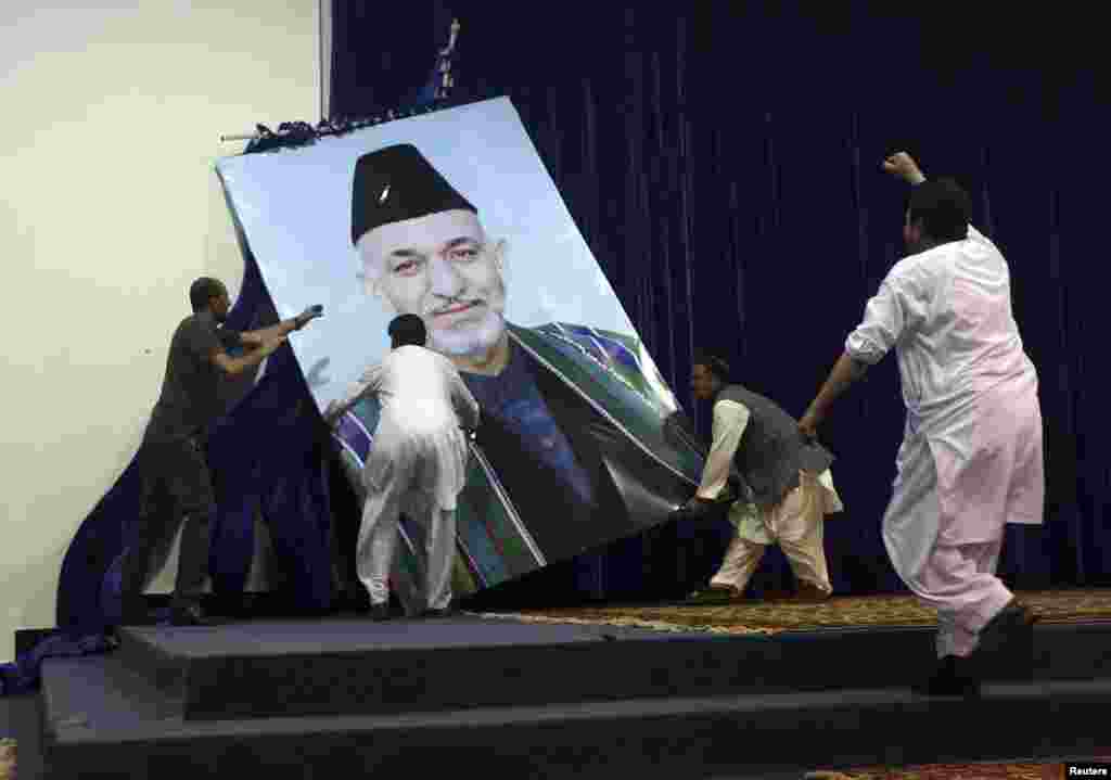 Pendukung capres Afghanistan Abdullah Abdullah menurunkan foto Presiden Hamid Karzai sebelum rapat di Kabul.