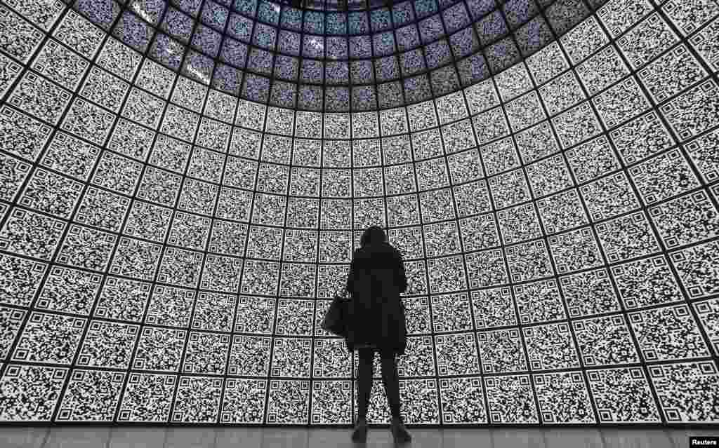 A visitor stands in front of QR-codes information panels during a ceremony to open an information showroom dedicated to the Zaryadye park project in central Moscow, Russia. The showroom, shaped as a dome which houses exhibition halls covered with QR-codes information panels and displaying digital illustration of the project, was opened by Moscow's Mayor Sergei Sobyanin on the site of the future park in a few minutes walk distance from Red Square and the Kremlin, according to organizers.