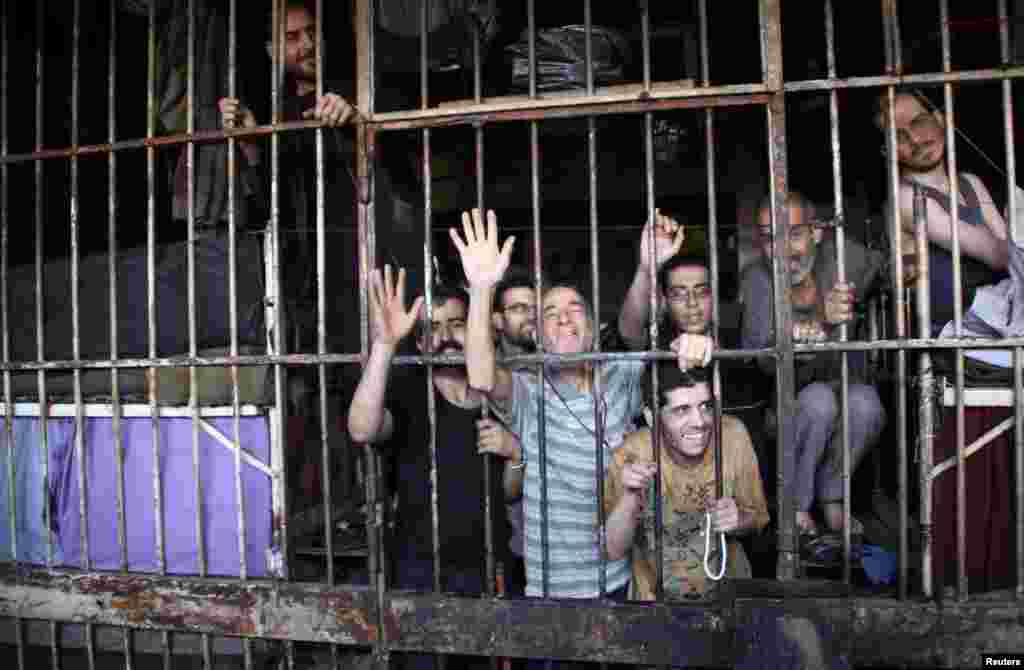Inmates gesture from behind bars in Aleppo's main prison, May 22, 2014.
