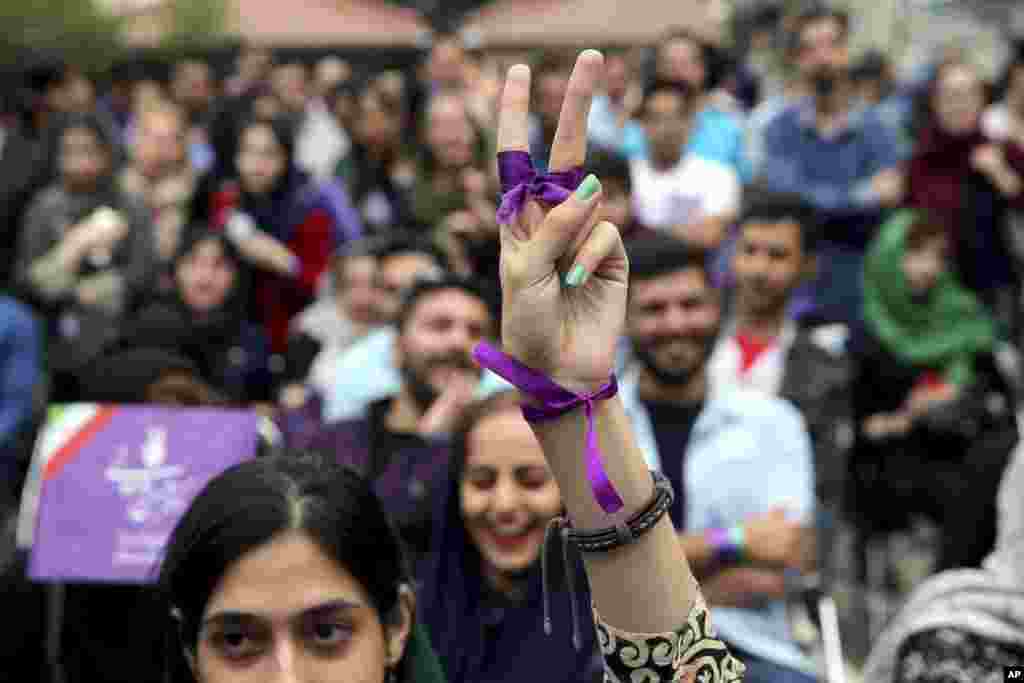 A supporter of Iran's President Hassan Rouhani, who is running for a second term in office, makes a V sign as she watches a live televised debate outside Rouhani campaign headquarters in Tehran.