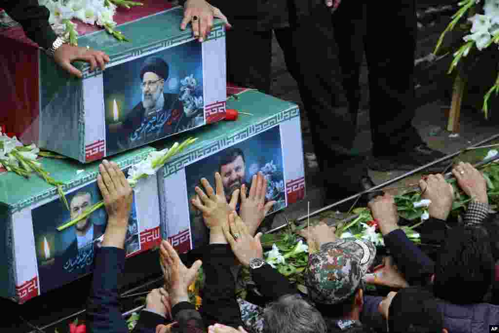 In this photo provided by Fars News Agency, mourners try to touch the coffins of Iranian President Ebrahim Raisi, top, Foreign Minister Hossein Amirabdollahian, left, and Raisi's chief bodyguard Gen. Mehdi Mousavi, who were killed in a helicopter crash on Sunday in a mountainous region of the country's northwest, during a funeral ceremony at the city of Tabriz. 
