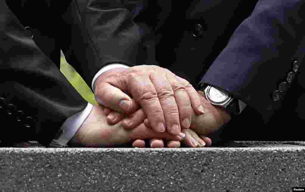 The hands of French President Francois Hollande and German President Joachim Gauck are seen during a stone-laying ceremony to mark the 100th anniversary of the100th anniversary of World War I, at the National Monument of Hartmannswillerkopf, in Wattwiller, eastern France, August 3, 2014.