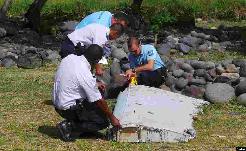 Des gendarmes et policiers français inspectent un morceau d'avion trouvé sur la plage de Saint-André, sur l'île de la Réunion, 29 juillet 2015.