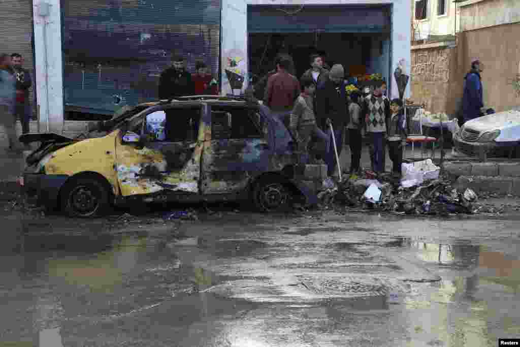 Warga memeriksa kerusakan yang disebabkan oleh bom bunuh diri yang dilakukan oleh organisasi Negara Islam Irak dan Levant di markas Brigade Tauhid dan Brigade Al-Fateh di Aleppo, 12 Januari 2014.