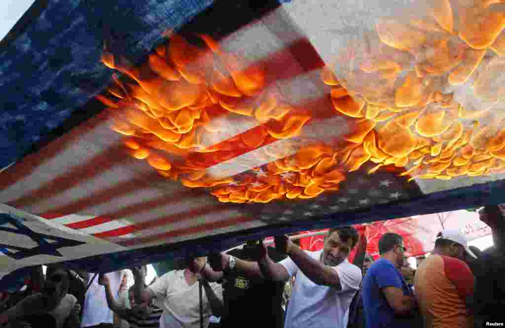 Lebanese and Palestinian protesters set fire to U.S. and Israeli flags during a demonstration to denounce Israeli air strikes on the Gaza strip, in Lebanon's southern port-city of Sidon.