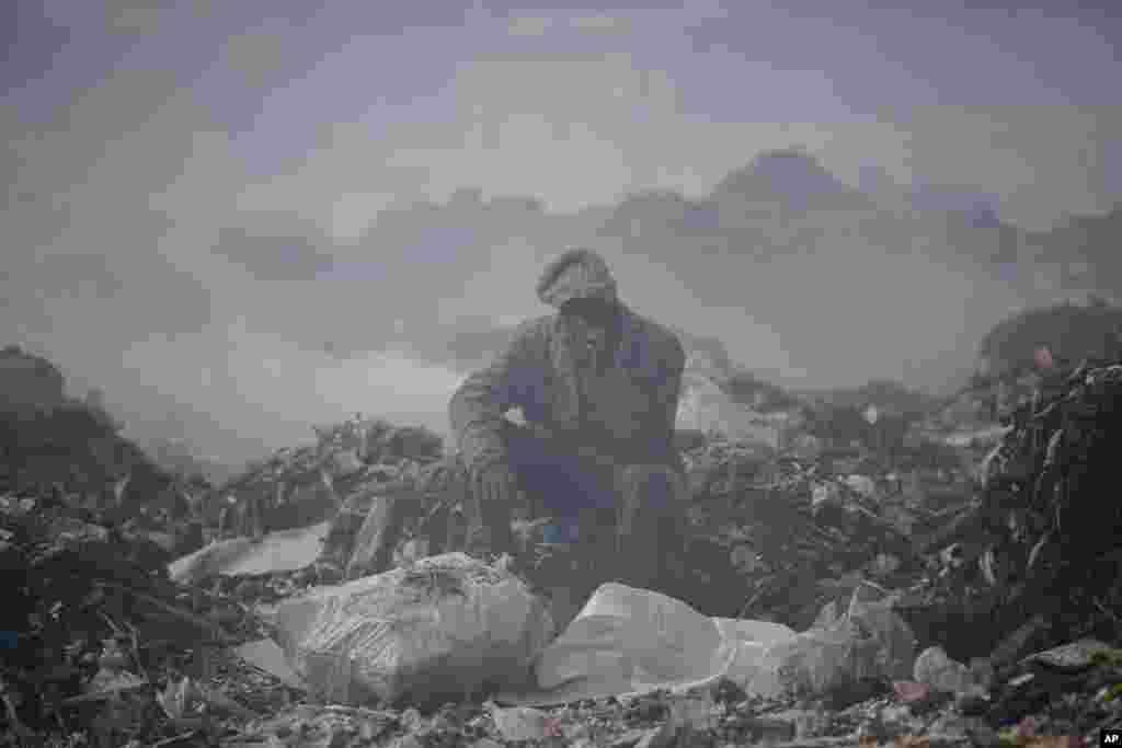A man who scavenges recyclable materials for a living rests on a mountain of garbage amidst smoke from burning trash at Dandora, the largest garbage dump in the capital Nairobi, Kenya, Sept. 7, 2021.