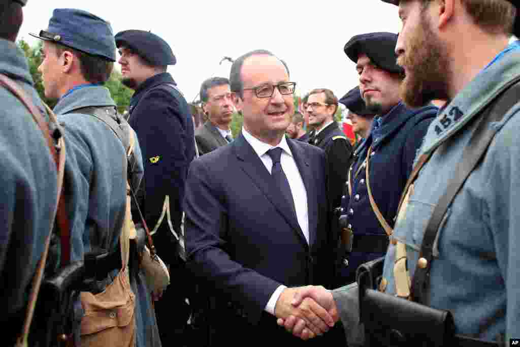 French President Francois Hollande shakes the hand of a man wearing a World War I uniform after a ceremony to mark the 100th anniversary of the outbreak of World War I, at the National Monument of Hartmannswillerkop, in Wattwiller, eastern France, Aug. 3, 2014.