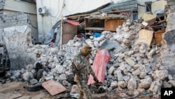 A soldier walks past rubble in the aftermath of an attack on the Afrik Hotel in Mogadishu, Somalia, Feb. 1, 2021. Al-Shabab claimed responsibility for the deadly assault.