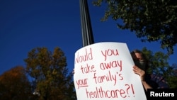 A protester holds a sign outside the U.S. Supreme Court building, as the court justices engage in arguments over the fate of Obamacare laws, in Washington, Nov. 10, 2020.