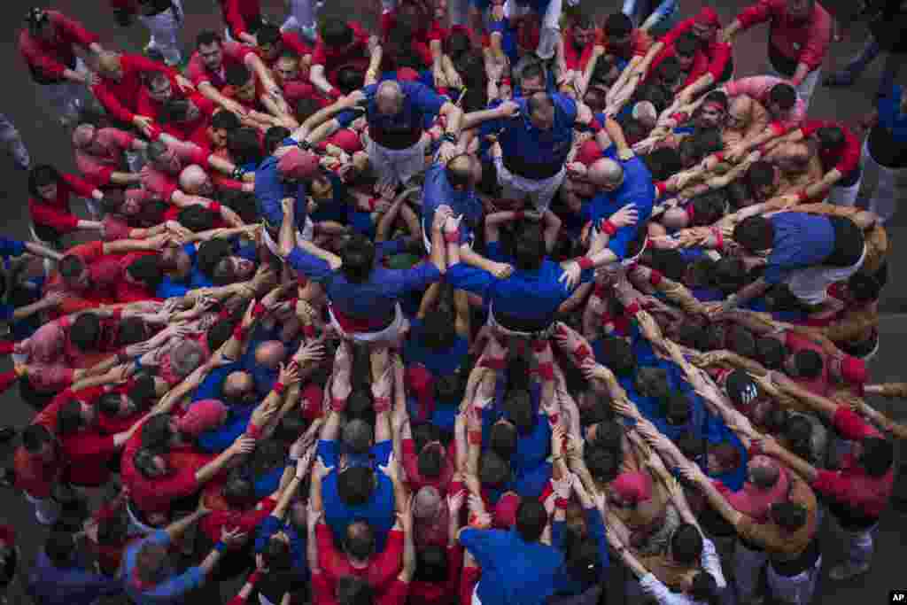 Para anggota kelompok Castellers "Vila de Gracia" mulai membentuk menara manusia yang disebut "castell" di lingkungan Barcelona Gracia, di Catalonia, Spanyol.