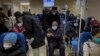 A man pushes an elderly woman past patients receiving intravenous drips in the emergency ward of a hospital, Jan. 3, 2023. 
