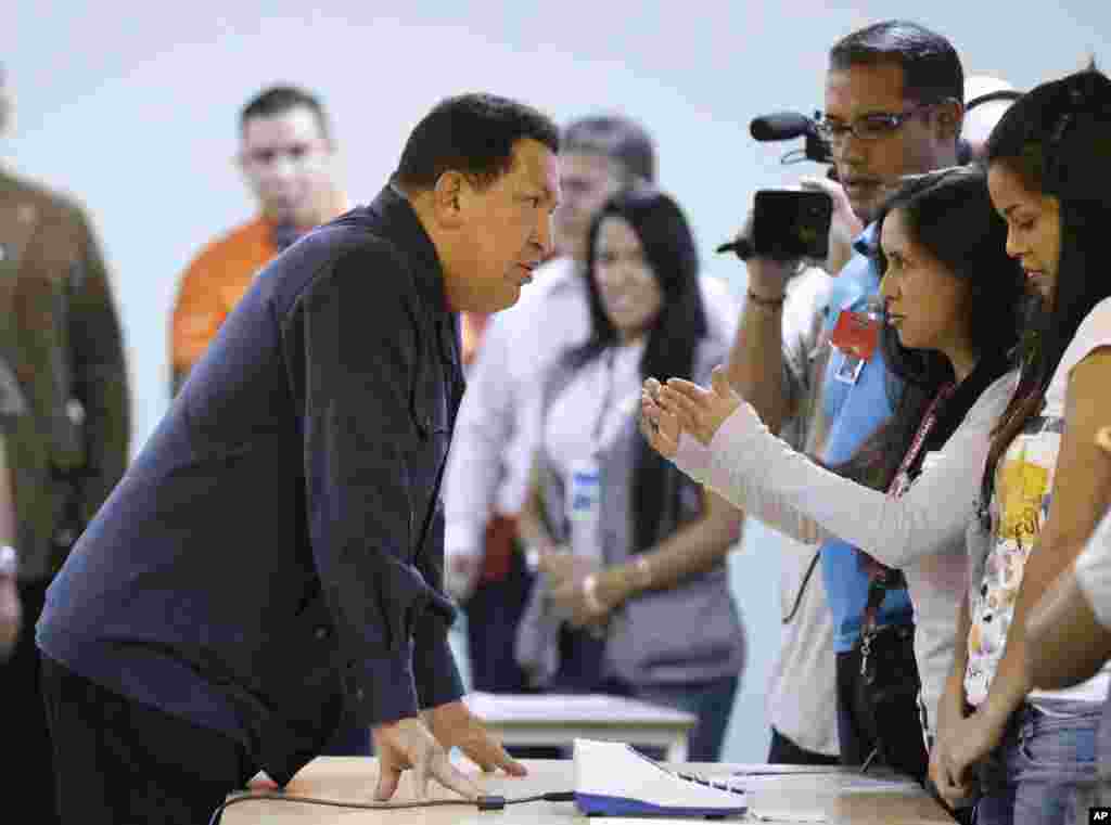 Chávez, izquierda, habla con un empleado en las elecciones durante las votaciones presidenciales en Caracas, el 7 de octubre de 2012.