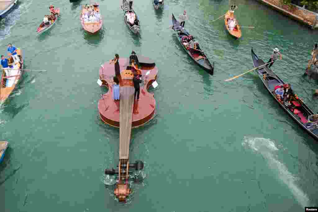 A string quartet plays onboard a violin-shaped boat, titled "Violin of Noah", that was built by artist Livio De Marchi in collaboration with Consorzio Venezia Sviluppo and is dedicated to people who have died from the disease, in Venice, Italy, Sept. 18, 2021.