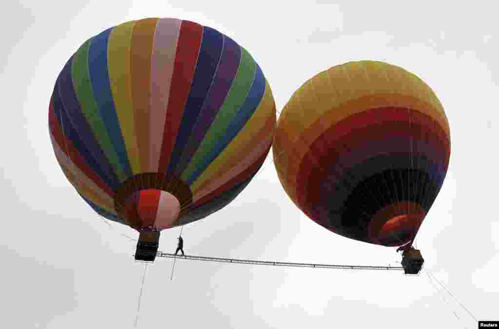 Aisikaier Wubulikasimu, atlet akrobat asal Uighur, China yang berusia 40-tahun berjalan pada kabel baja sepanjang 18m dengan lebar 5 cm yang direntangkan di antara dua balon udara di kota Shilin, provinsi Yunnan, China. Wubulikasimu merupakan pemegang dua rekor dunia Guinness pada tahun 2009 dan 2011.