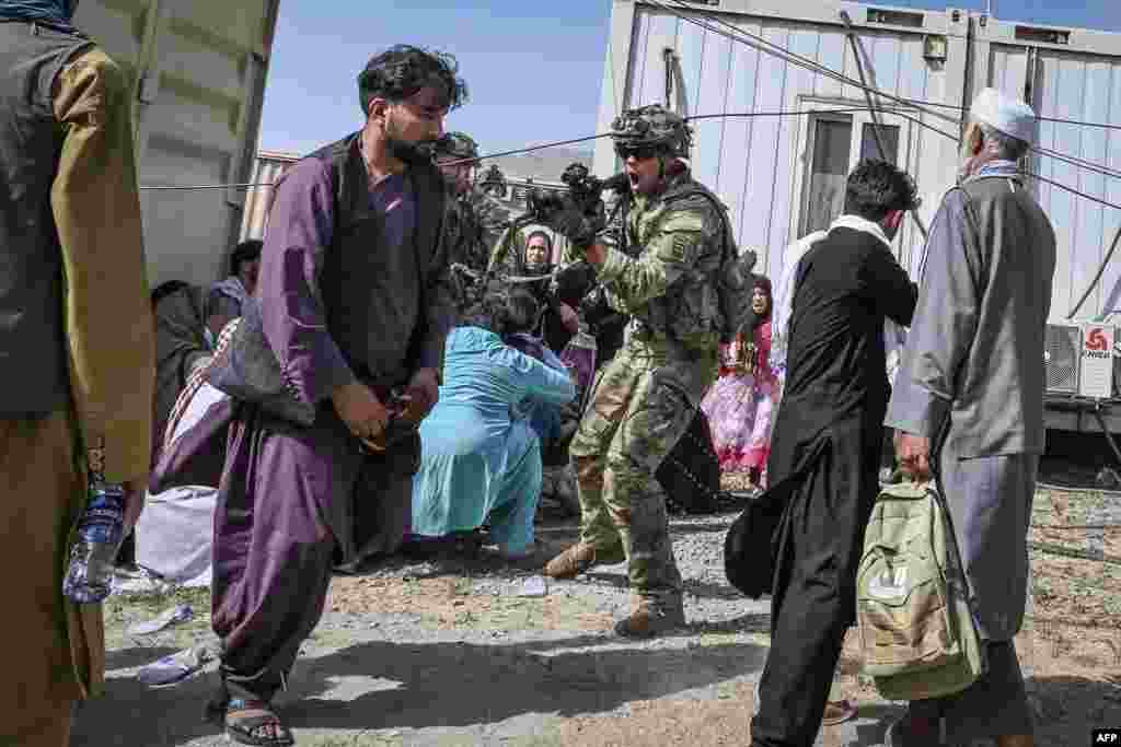 A U.S. soldier points his gun towards an Afghan passenger at the Kabul airport in Kabul as thousands of people mobbed the city's airport trying to flee the Taliban's hardline brand of Islamist rule.