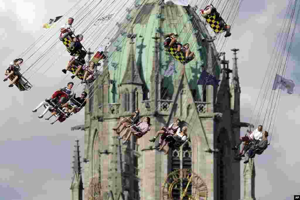 Warga menaiki "komedi putar" di depan gereja St. Paul pada festival Oktoberfest di Munich, Jerman.