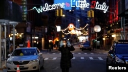 Una mujer con una máscara protectora y guantes se toma una fotografía selfie mientras camina por una calle Mulberry casi vacía en el barrio Little Italy de Manhattan durante el brote de coronavirus en la ciudad de Nueva York, EE. UU., 18 de marzo de 2020.