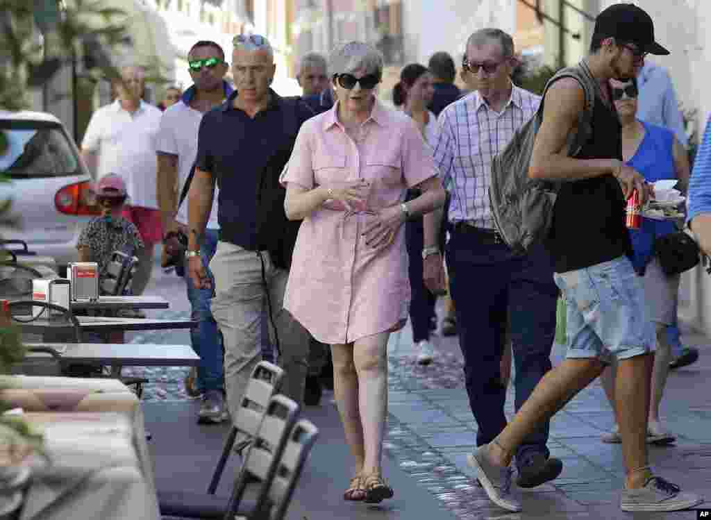 Britain Prime Minister Theresa May, left, walks with her husband Philip in Desenzano del Garda, by the Garda lake in northern Italy. May is spending her holidays in northern Italy.