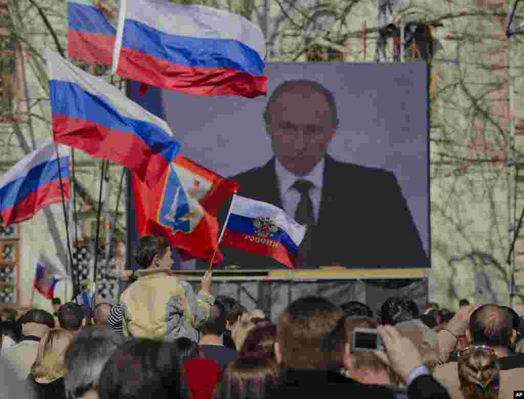 Orang-orang pro-Rusia menonton siaran langsung pidato Presiden Rusia Vladimir Putin tentang Krimea di Sevastopol, Krimea, 18 Maret 2014.