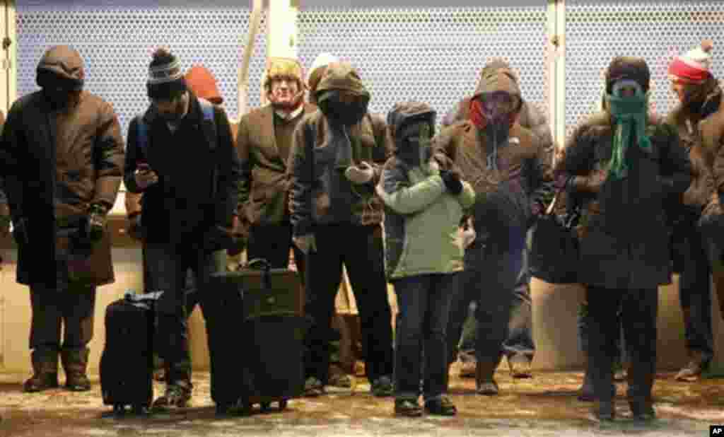 Komuter berkumpul di bawah lampu penghangat di salah satu jalur komuter popluer Chicago "El" sambil merasakan angin yang dingin menusuk jauh di bawah nol derajat, 6 Januari 2014.