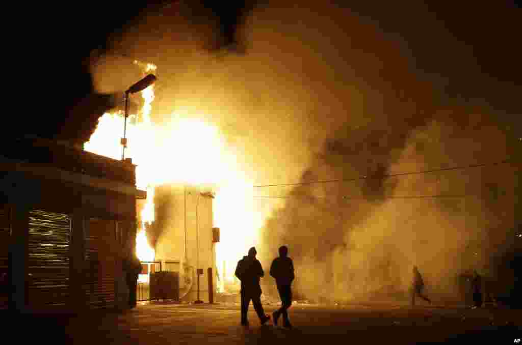 People walk near a storage facility on fire after the announcement of the grand jury decision, Ferguson, Missouri, Nov. 24, 2014.