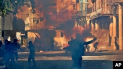 Polisi anti huru hara menembakkan gas air mata saat memblokir Rasheed Street saat bentrokan dengan demonstran anti-pemerintah di Baghdad, Irak, 22 November 2019. (Foto: AP)