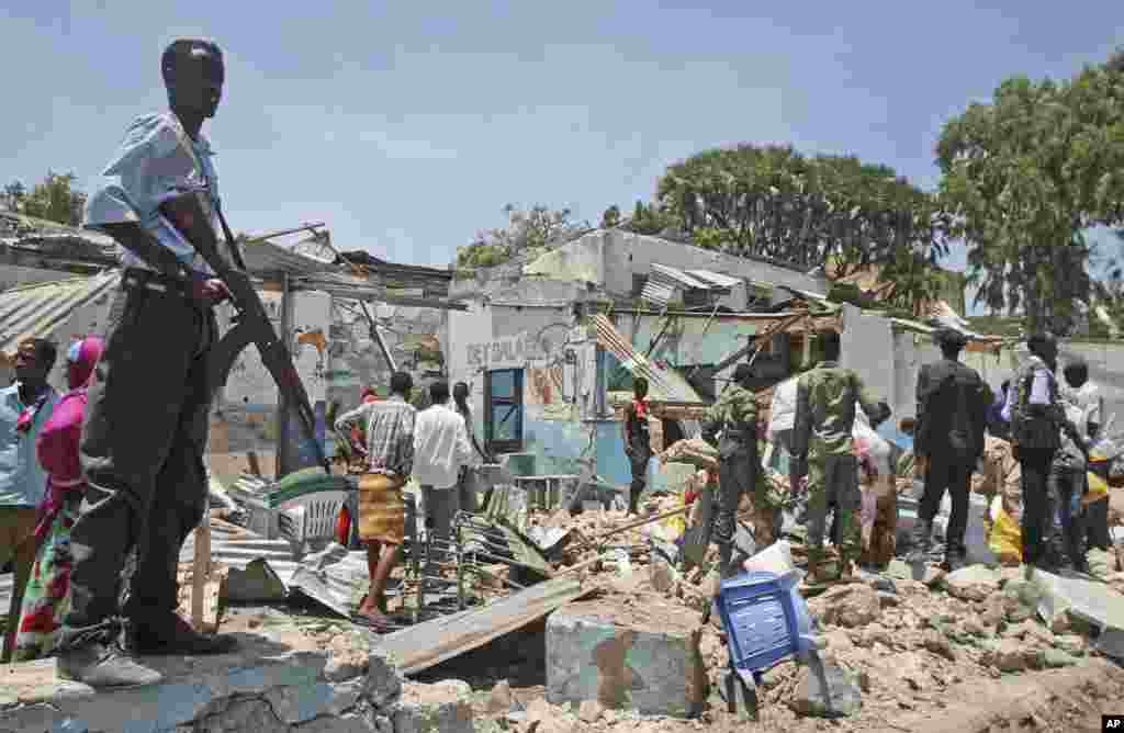 A soldier stands guard near destroyed shops after an explosion in Mogadishu, Somalia, March 18, 2013.