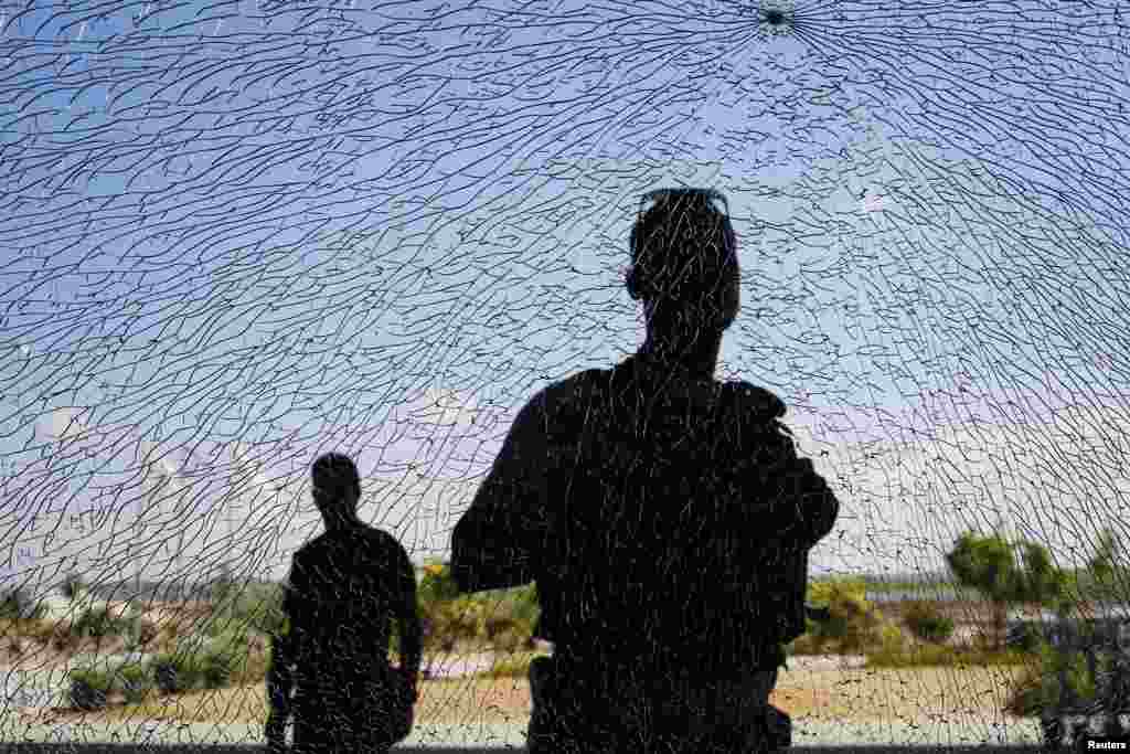 Israeli security personnel look at a window damaged by shrapnel after a short-range rocket landed near the Erez Crossing, a pedestrian/cargo terminal on the Israeli Gaza Strip barrier, July 16, 2014.