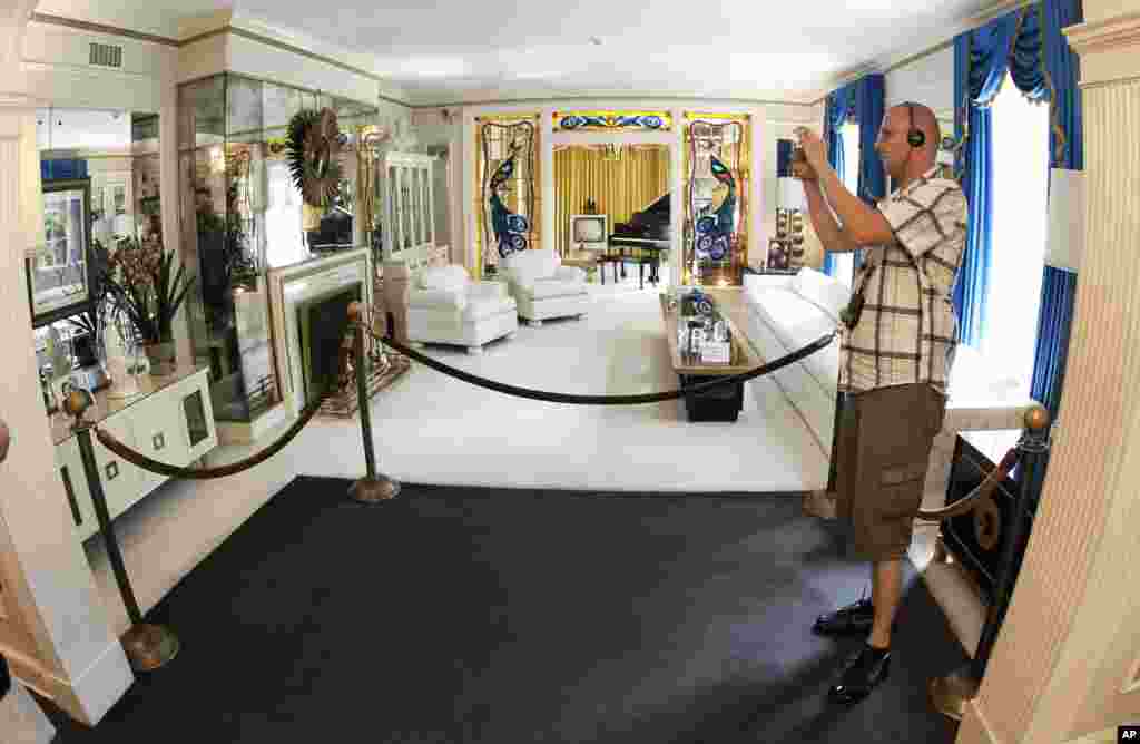 This Aug. 2010 photo shows a tourist viewing the living room at Graceland, Elvis Presley's home in Memphis, Tenn. Graceland opened for tours on June 7, 1982. They sold out all 3,024 tickets on the first day.