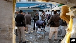 FILE - Pakistani security officials examine the site of a suicide attack in Mardan, Pakistan, Dec. 29, 2015.