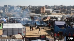Palestinianos aguardam por uma porção de alimentos num centro de distribuição a sul de Khan Yunis, no sul da Faixa de Gaza, a 17 de dezembro de 2024, no meio da guerra em curso entre Israel e o movimento palestiniano Hamas.