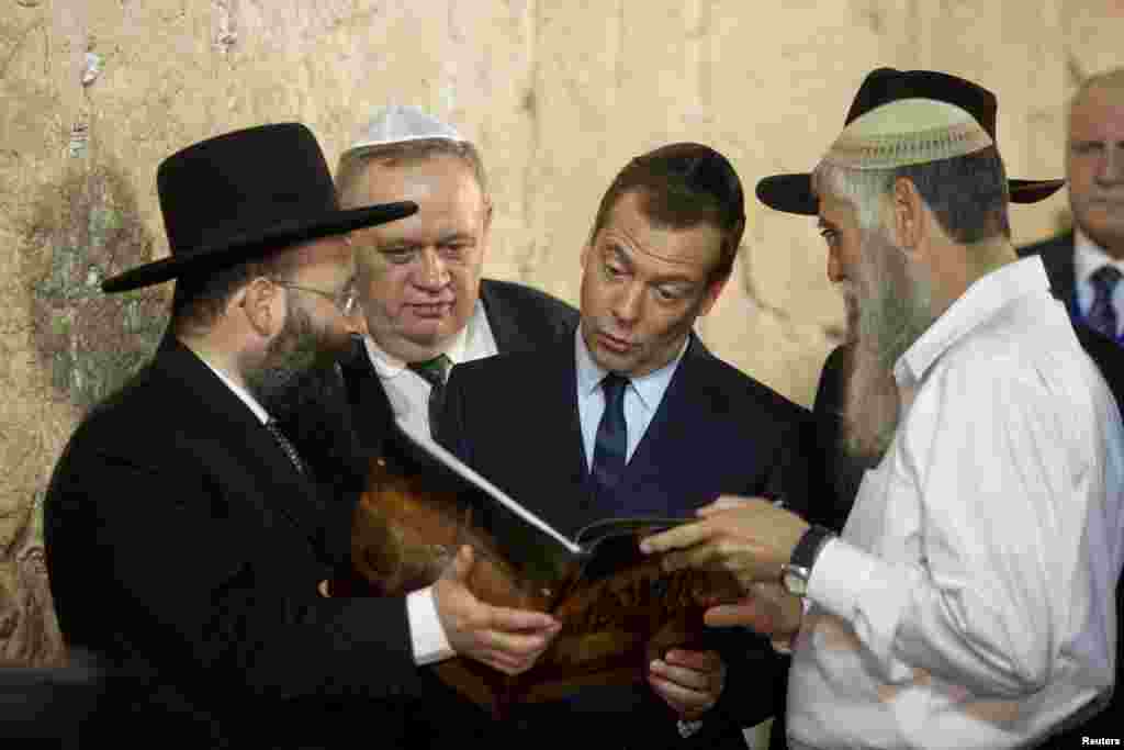 PM Rusia Dmitry Medvedev (tengah) melihat buku yang ditunjukkan kepadanya saat mengunjungi Tembok Ratapan di Yerusalem.