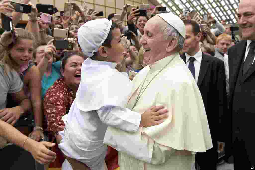 Pope Francis lifts a child dressed like him as he greets faithful at the end of his weekly general audience, in the Paul VI Hall, at the Vatican.