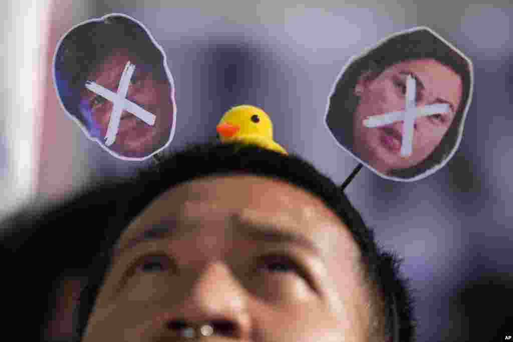 A protester looks at the crossed-out images of Philippine President Ferdinand Marcos Jr., left, and Vice-President Sara Duterte as he joins a protest against a plan by some lawmakers to change parts of the constitution, in Manila, Philippines.