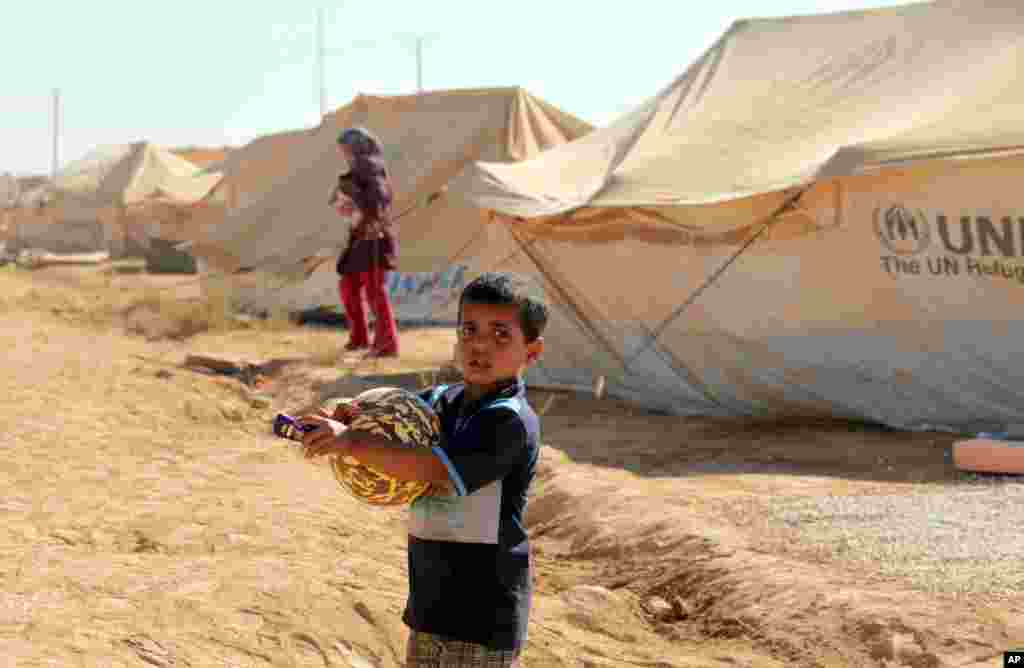 Một bé trai Syria trong trại tị nạn Zaatari ở Mafraq, Jordan, ôm gói đồ chơi, quần áo, và tiền, tặng cho trẻ em Hồi giáo vào ngày đầu tiên lễ Eid al-Fitr của người Hồi giáo, 19/8/12