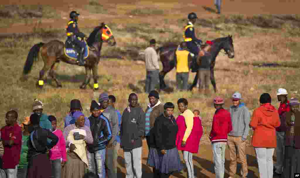 South Africans queue to vote as mounted police provide security near a polling station that was burned down overnight. A tent was erected to replace the station in the politically sensitive mining town of Bekkersdal, South Africa, May 7, 2014.