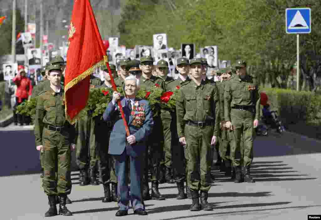 Russian World War II veteran Alexey Samokhin (C), 89, carries a red flag as he leads a procession during the Victory Day celebration in Divnogorsk, near Russia's Siberian city of Krasnoyarsk.