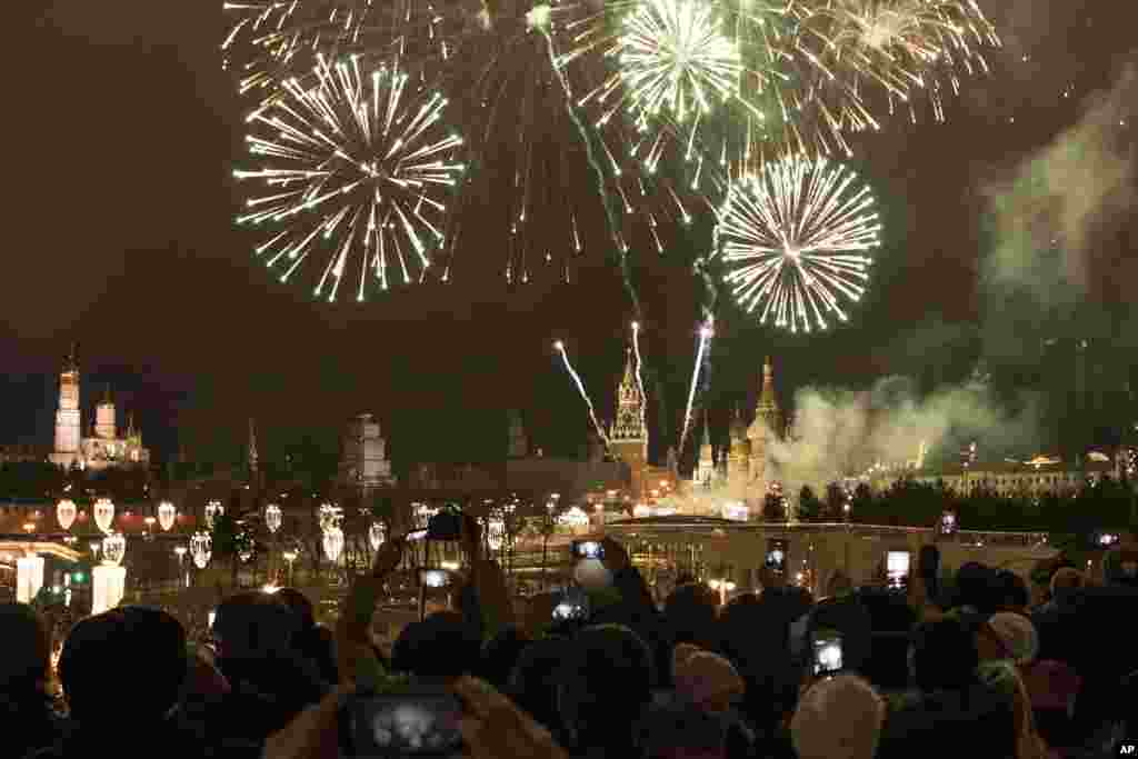 People take pictures as fireworks explode over the Kremlin, during New Year celebrations in Moscow, Russia, Monday, Jan. 1, 2018. New Year is Russia's major gift-giving holiday. (AP Photo/Denis Tyrin)
