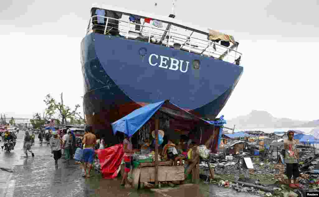 Typhoon survivors sell goods in a makeshift store next to a ship that was swept ashore by Super Typhoon Haiyan last month, in Tacloban city in central Philippines.