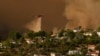 Un hélicoptère largue de l'eau sur les maisons alors que l'incendie de Palisades progresse dans le Mandeville Canyon, le samedi 11 janvier 2025, à Los Angeles.