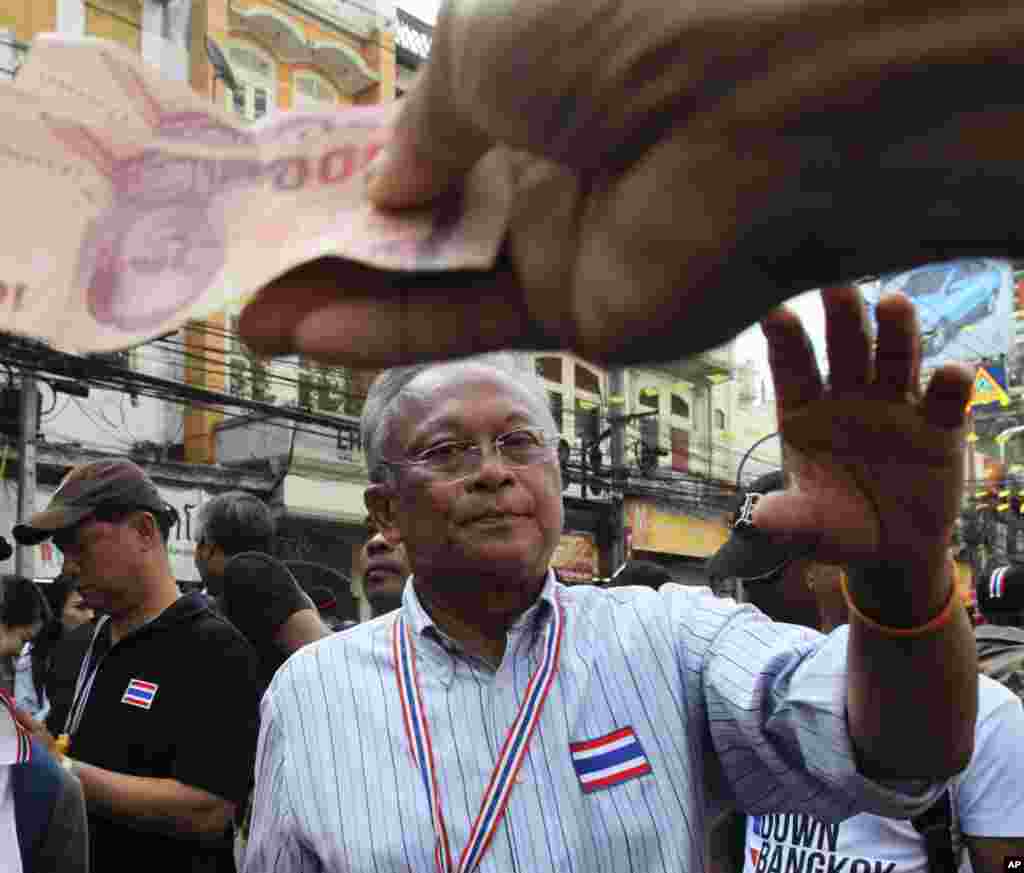 Anti-government protest leader Suthep Thaugsuban collects donations from supporters during a march through streets in Bangkok, Feb. 7, 2014.